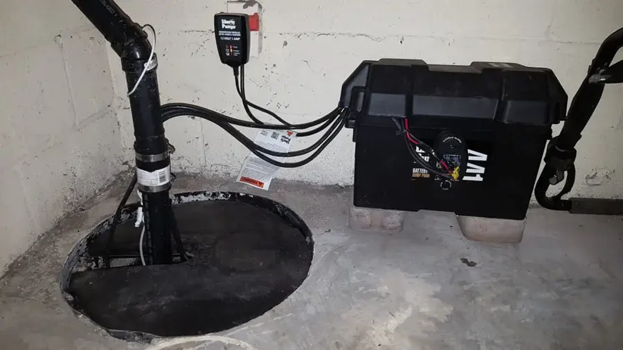 Sump pit with a battery backup pump and an alarm on a basement floor