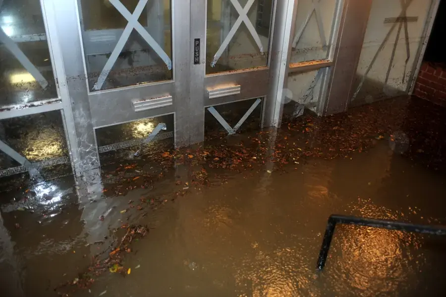 Storm water flooding into a storefront through glass doors