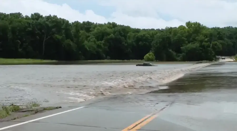 Storm water flowing over a road beside a wooded creek bottom in Missouri