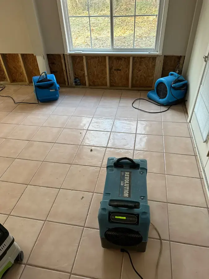Air movers and an LGR dehumidifier drying a room with the lower drywall cut out