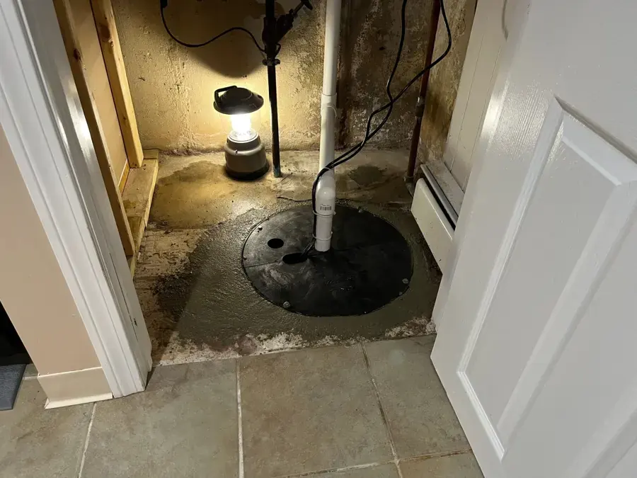 Sump pit in a basement utility closet lit by a lantern during a power outage